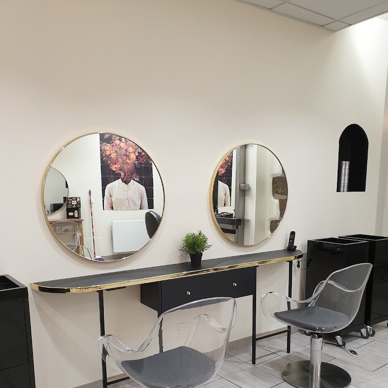 Les deux miroirs ronds dorés et les postes de coiffage clairs du salon