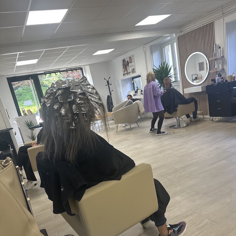 Le salon L'évidence, une cliente en cours de couleur, fauteuils clairs et grandes fenêtres